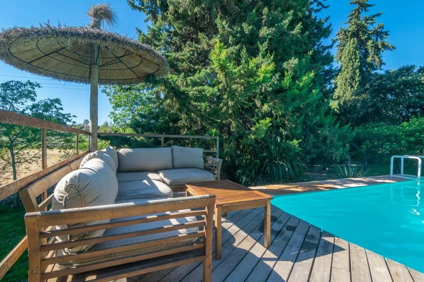 Una zona de asientos junto a la piscina, con una mesa de madera.