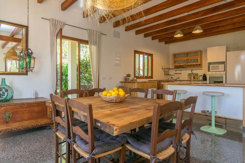 Comedor con una mesa grande de madera y una cocina abierta al fondo.
