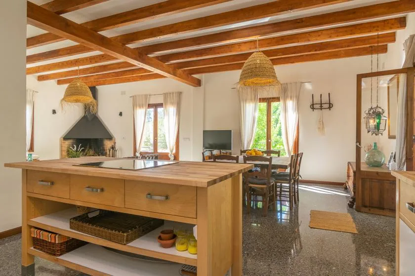Una cocina y comedor rústicos con una isla de madera, vigas expuestas y una chimenea.