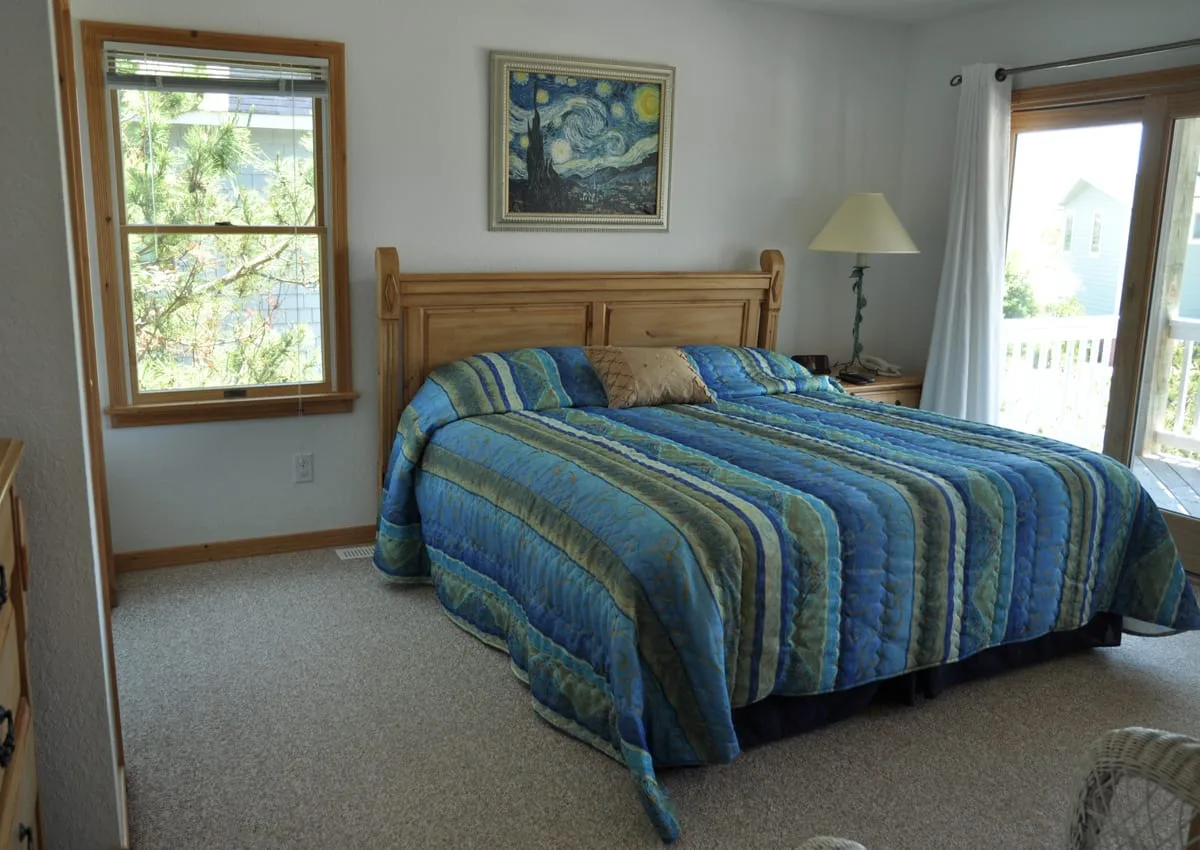 Un dormitorio con una cama de madera, ropa de cama azul a rayas y una ventana.