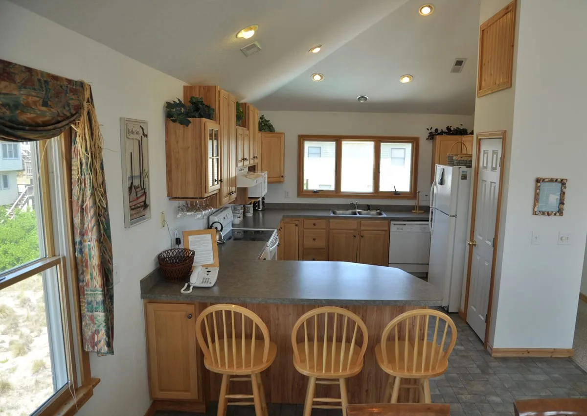 Una cocina luminosa con gabinetes de madera, una barra central y asientos.