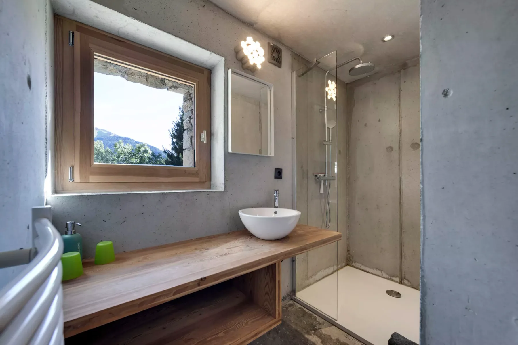 Un baño con mueble de madera, lavabo sobre encimera y ducha de vidrio.
