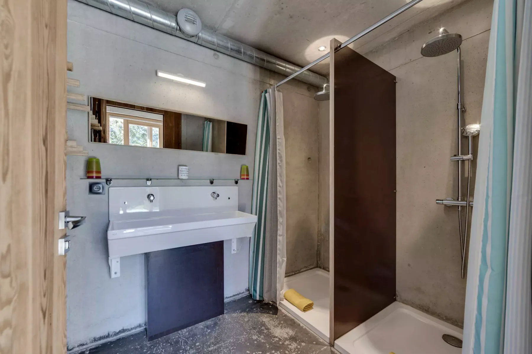 Un baño con lavabo y ducha detrás de una mampara de vidrio.