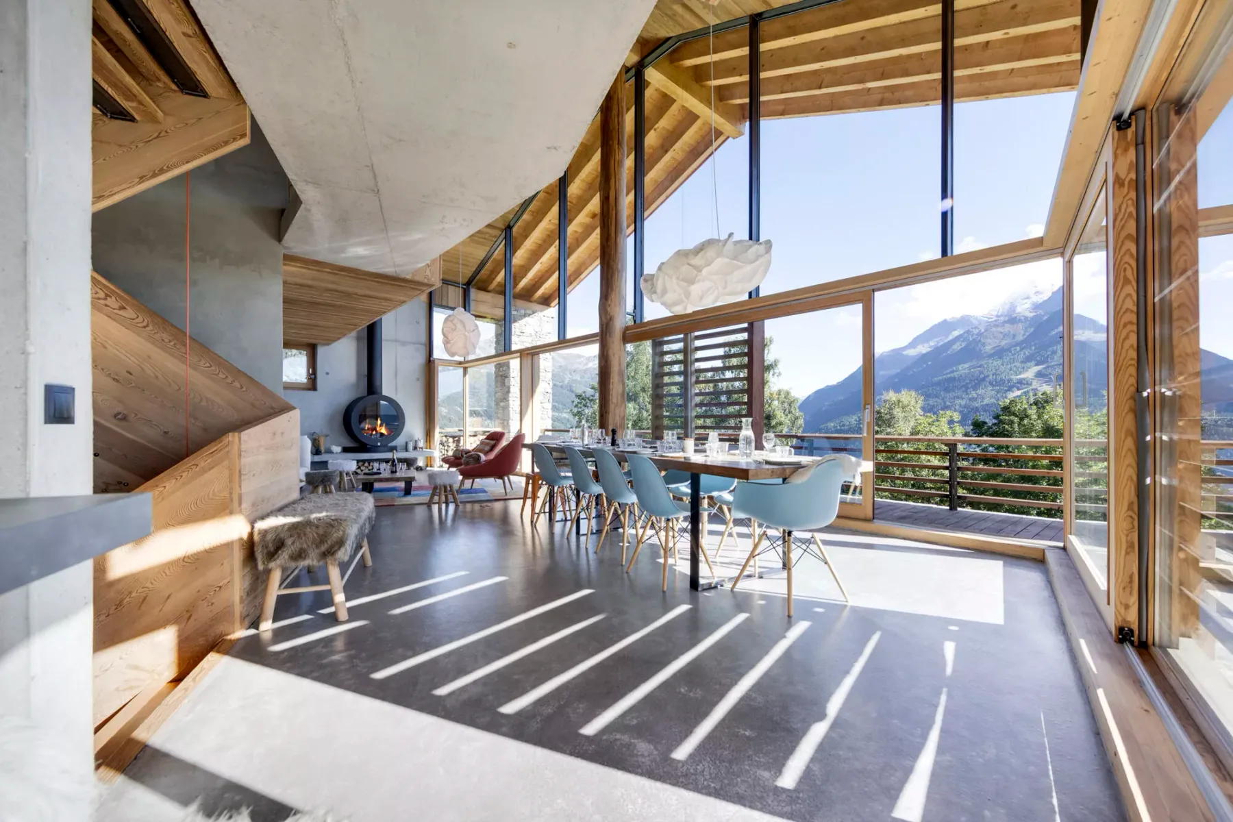 Un comedor luminoso con una mesa larga y vistas a las montañas por grandes ventanales.