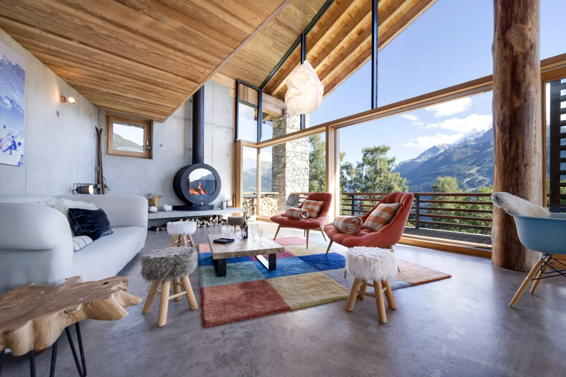 A living room with seating around a coffee table and large windows overlooking mountains.