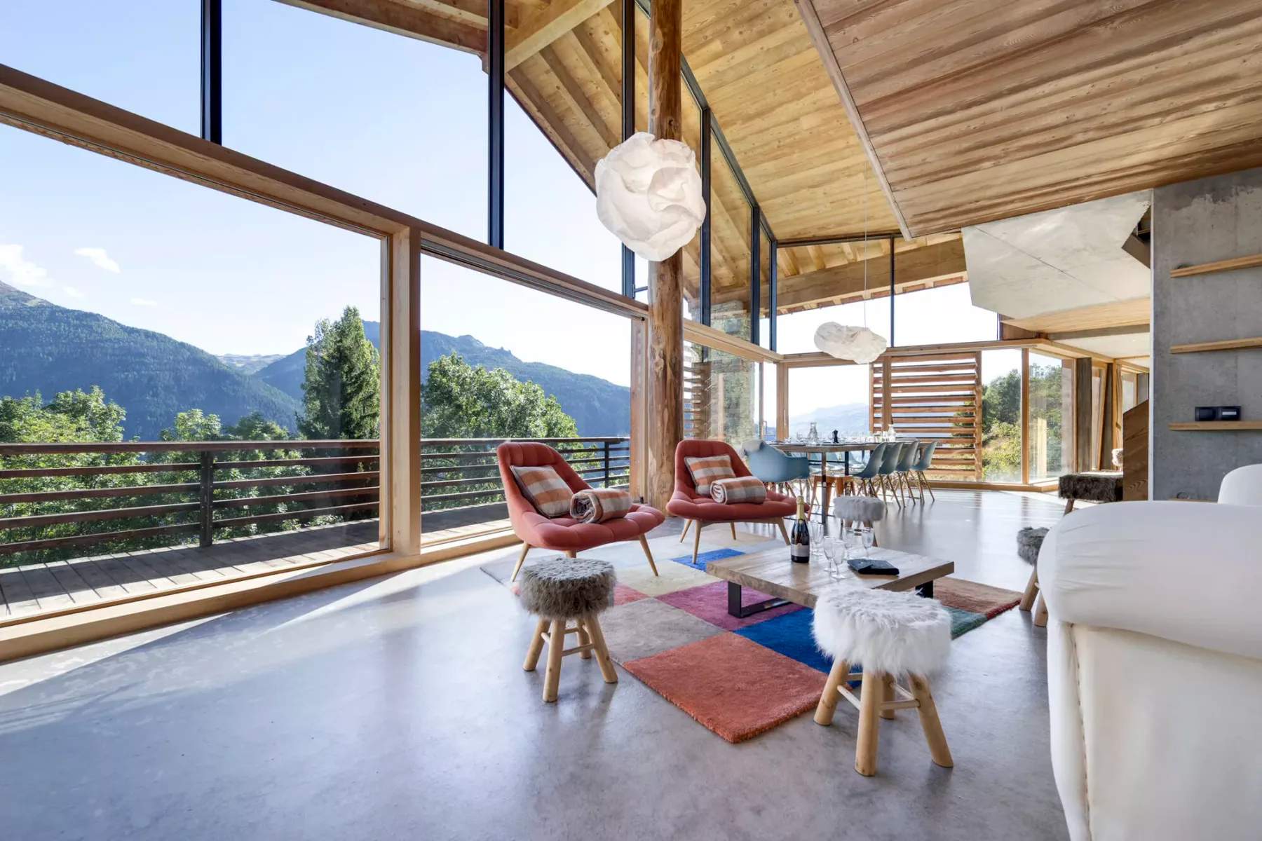 Una luminosa sala de estar con asientos y grandes ventanales con vistas a las montañas.