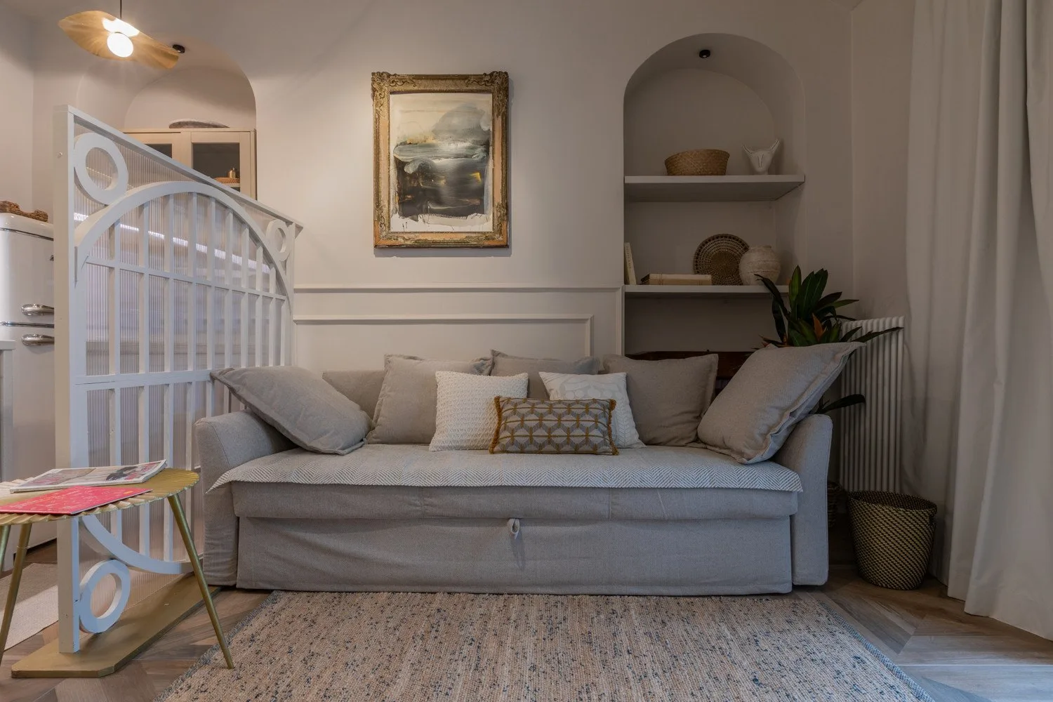 A living room with a sofa beneath framed artwork and built-in shelves.