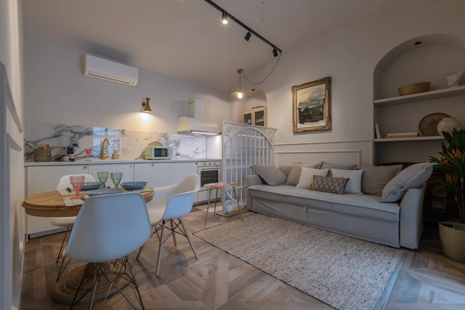 A living room with a sofa and dining table beside a compact kitchen.