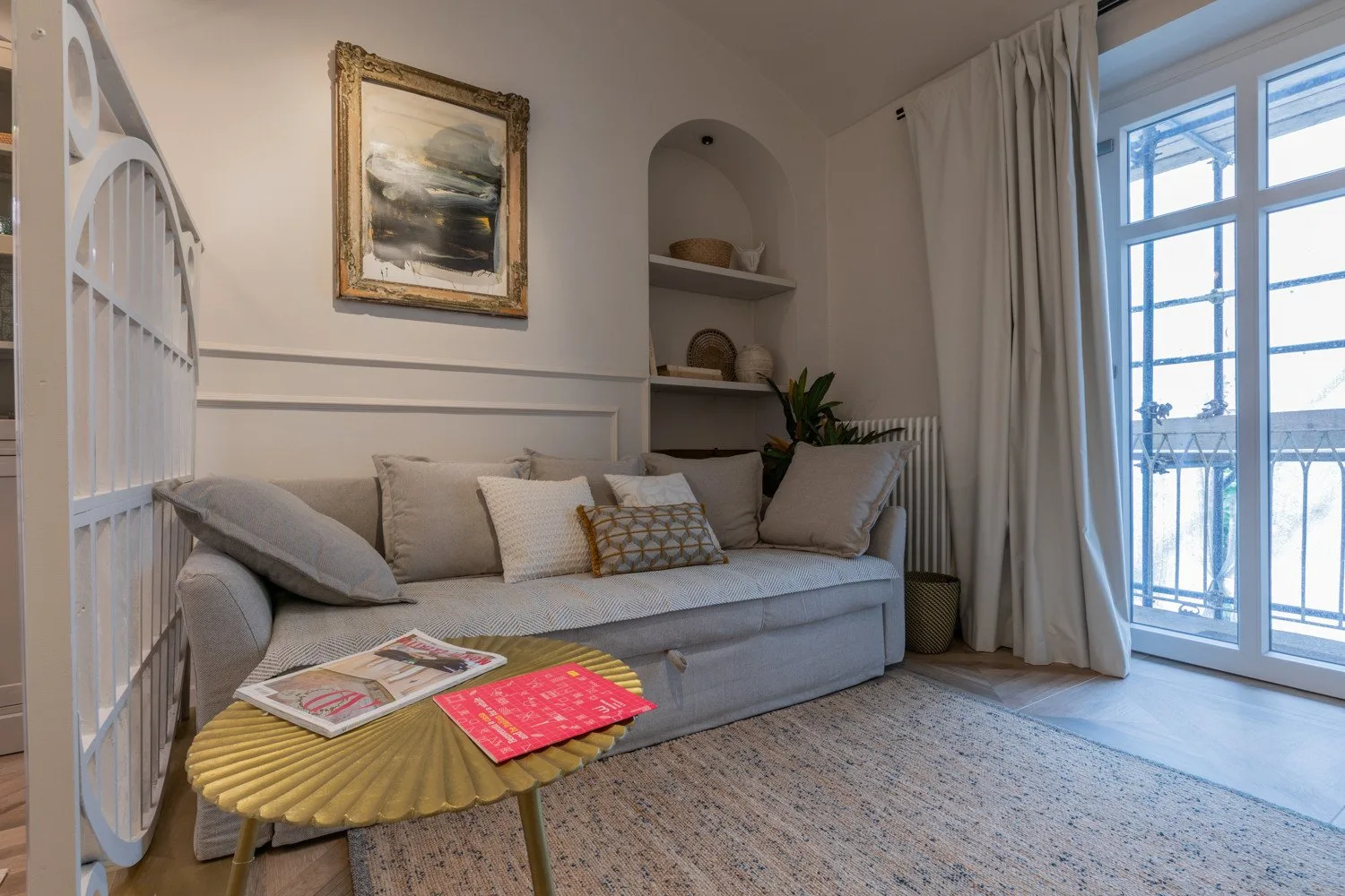 A sitting area with a cushioned bench, small table, and tall windows.