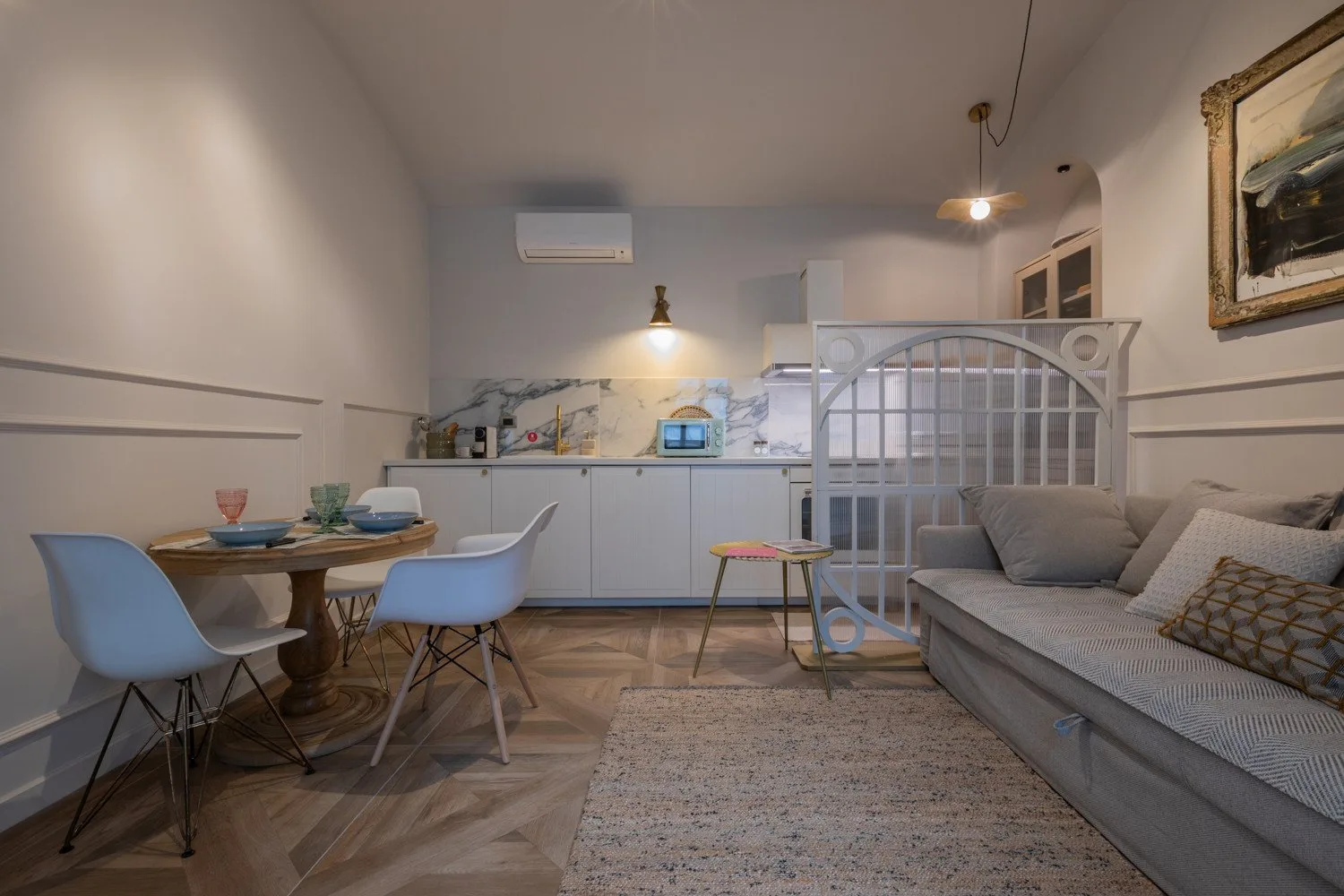 A compact living and kitchen area with a dining table and sofa.