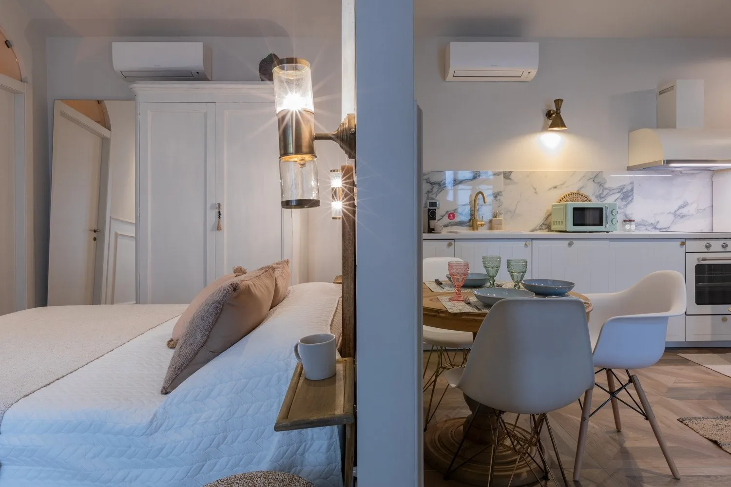 A bedroom with a bed beside a compact kitchen and dining area.