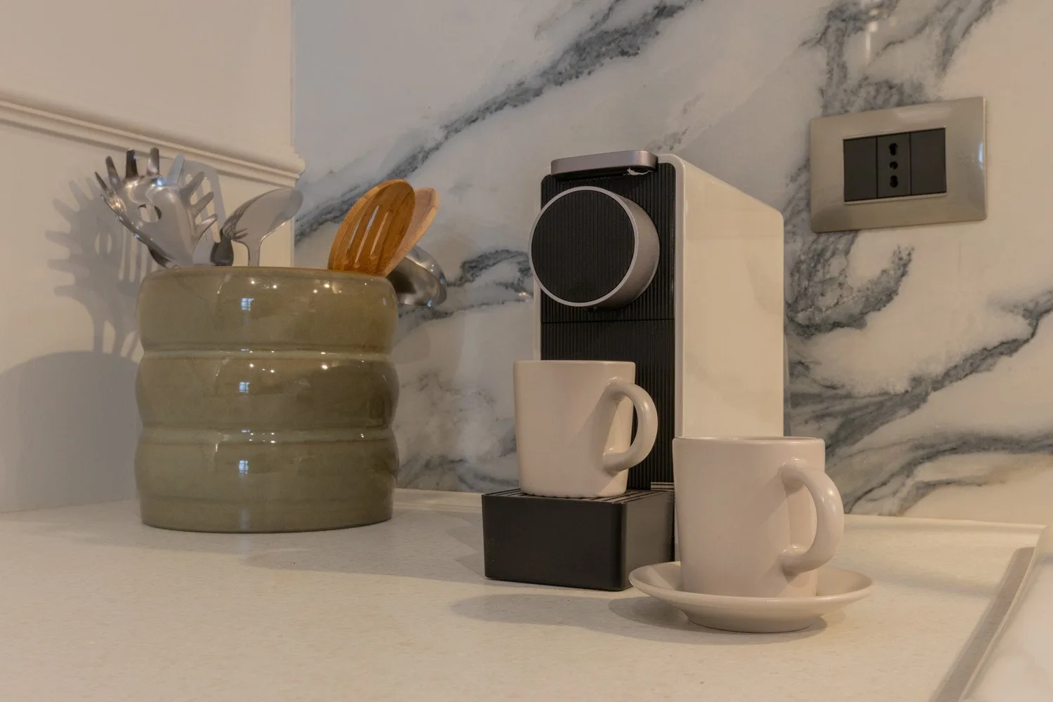 A countertop coffee setup includes a coffee machine and two cups.