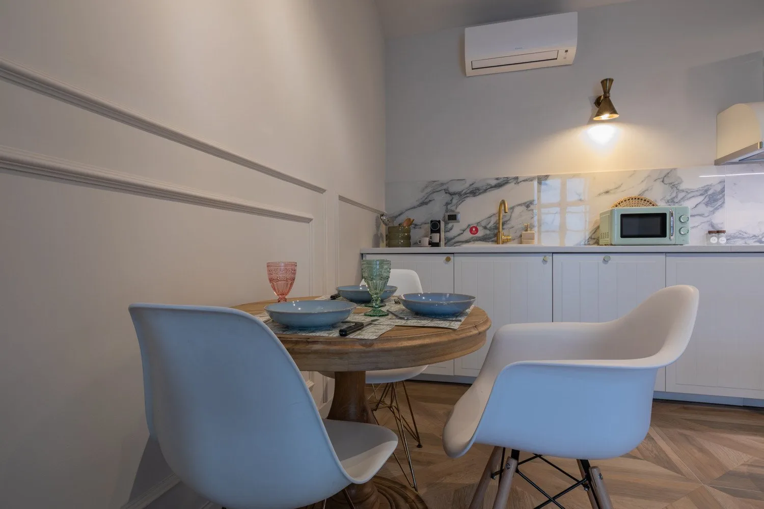 A dining area with a round table and pale blue seating beside a kitchen.
