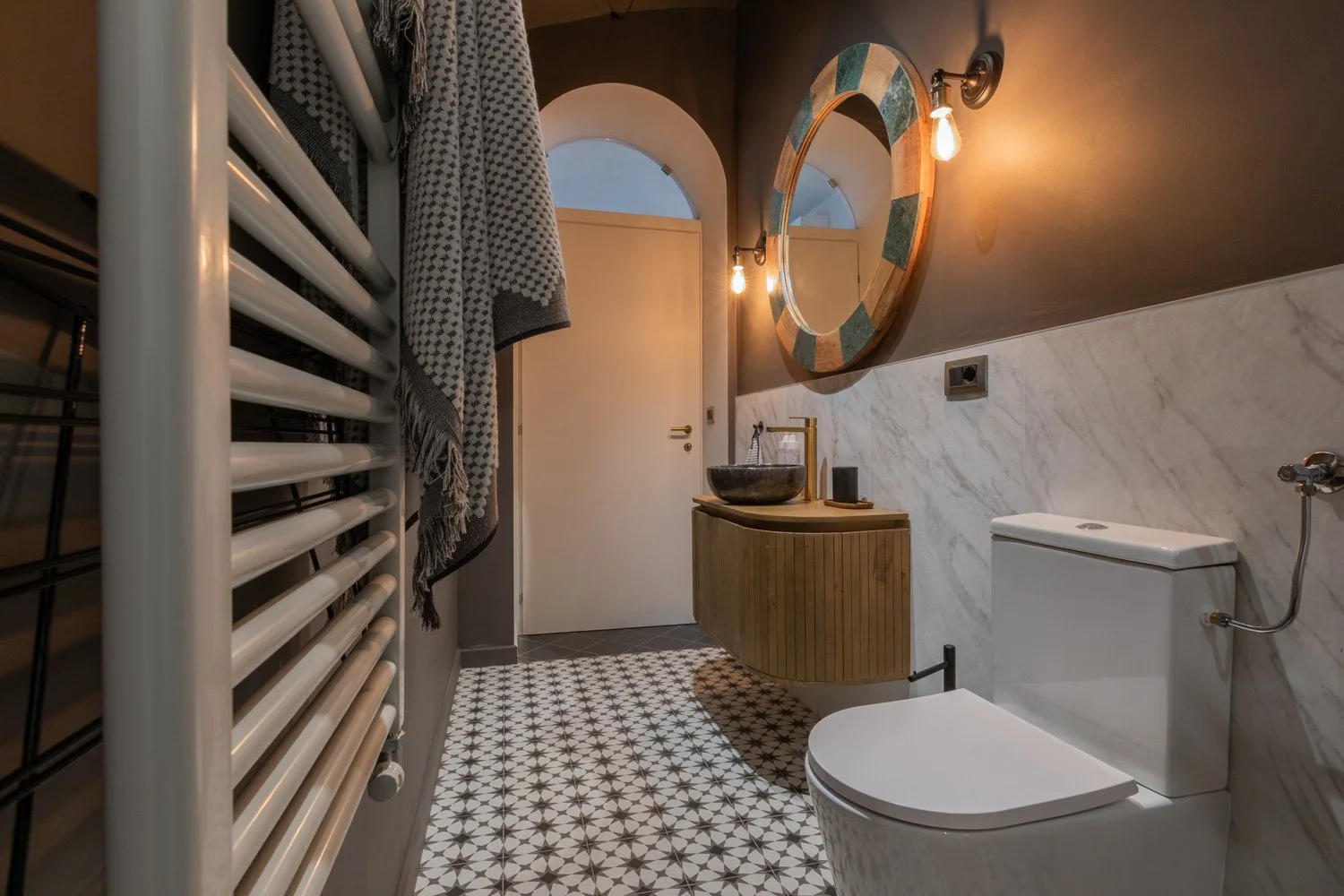 A bathroom with patterned floor tiles, a sink, and a toilet.