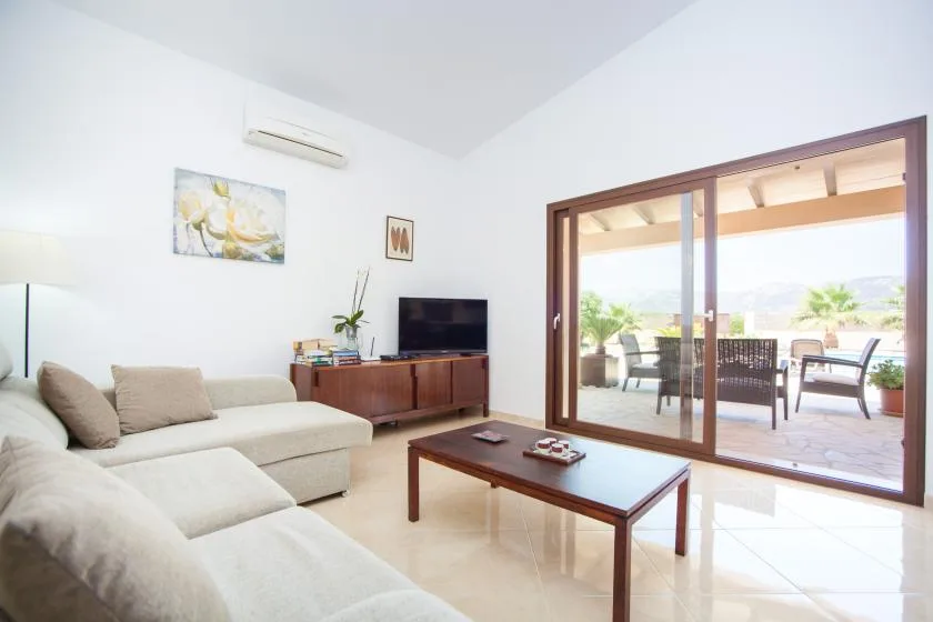A bright living room with seating and a coffee table beside large glass doors.