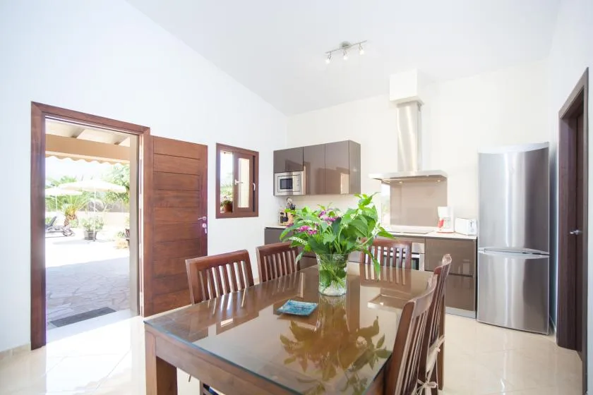A bright kitchen and dining area with a wooden table and stainless steel refrigerator.