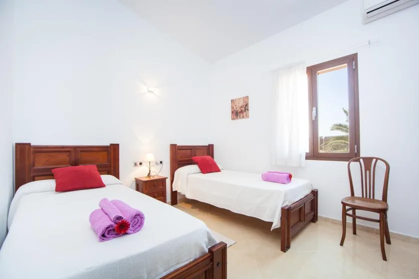 A bright bedroom with two beds and a window.