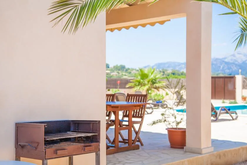 A shaded patio with an outdoor dining table and a built-in grill.