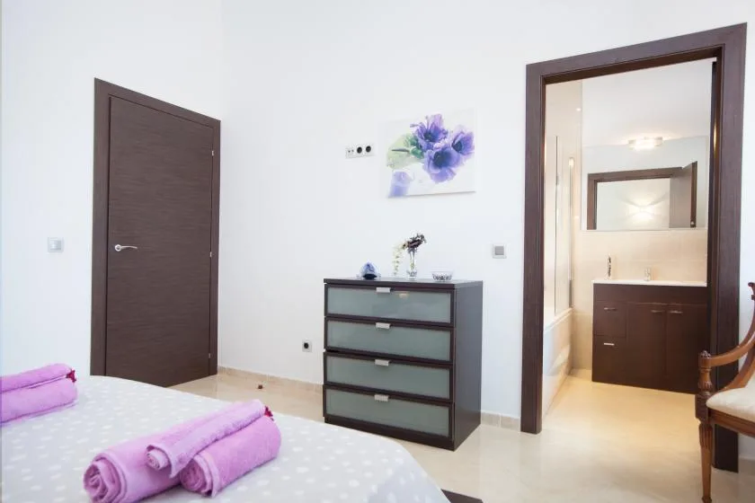 A bedroom with a bed, a dresser, and an open doorway to a bathroom.