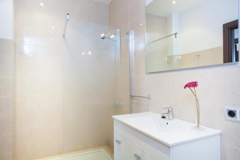 A bright bathroom with a glass shower, white vanity, and large mirror.