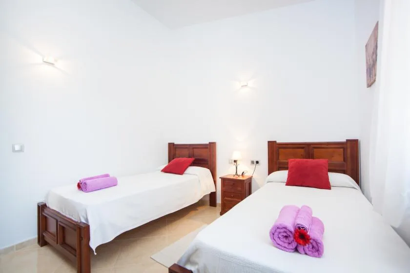 A bright bedroom with two beds and folded towels.