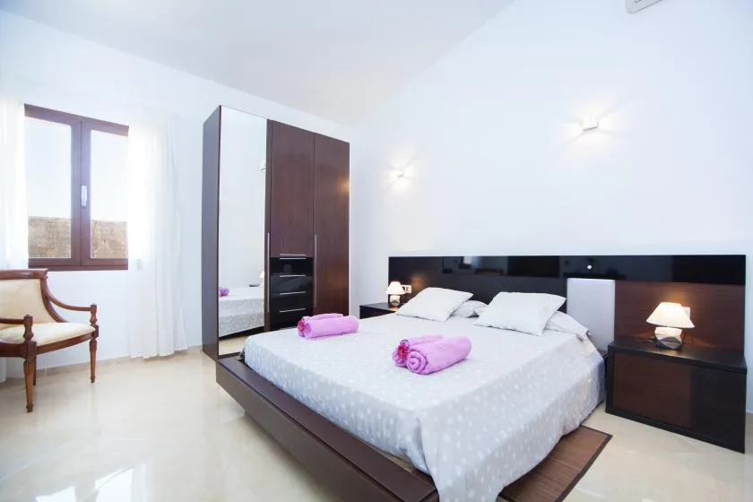A bright bedroom with a large bed, bedside tables, and a window.