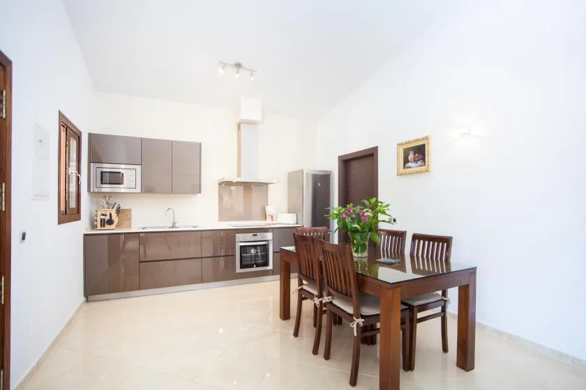 A bright kitchen and dining area with dark cabinetry and a wooden table.