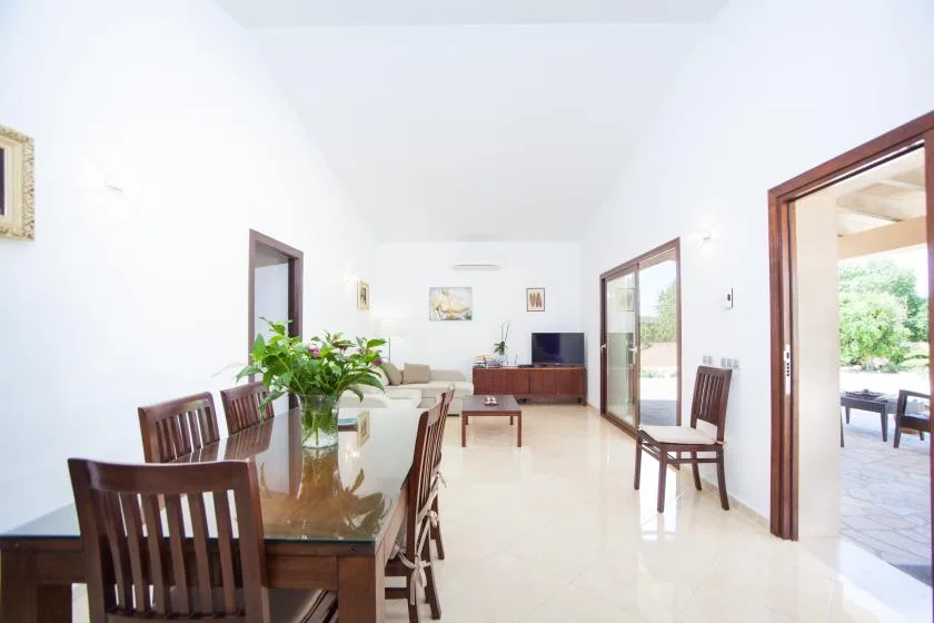A bright dining and living area with a wooden table and seating.
