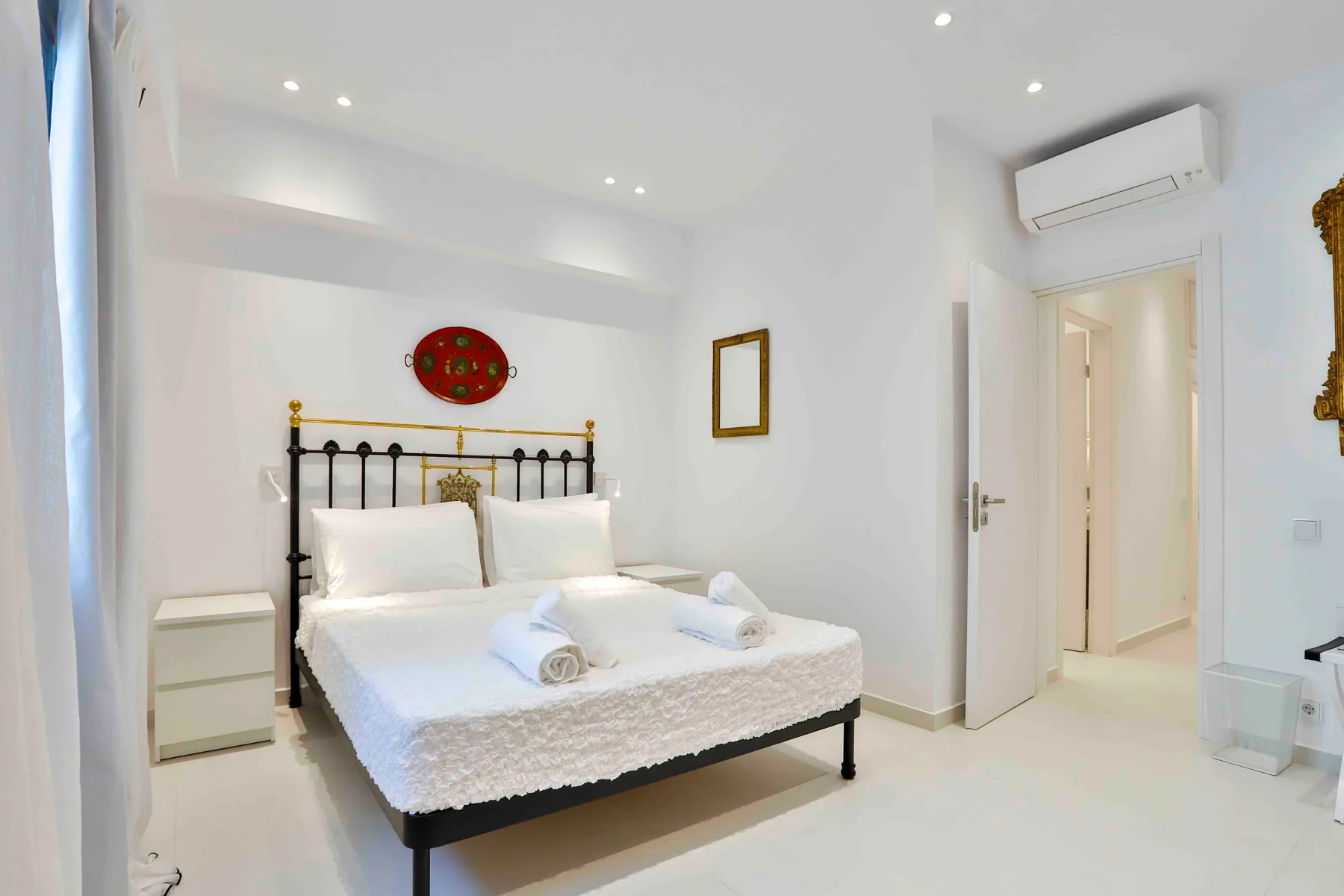 Un dormitorio luminoso con una cama doble y ropa de cama blanca.
