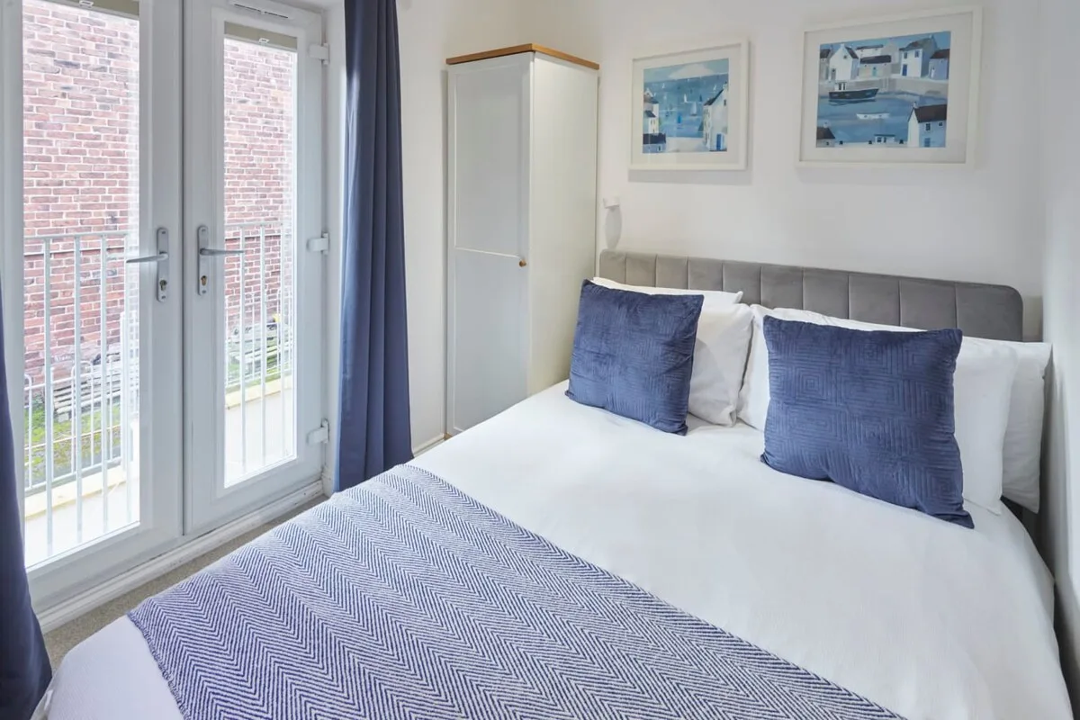 A bright bedroom with a neatly made bed and glass doors.