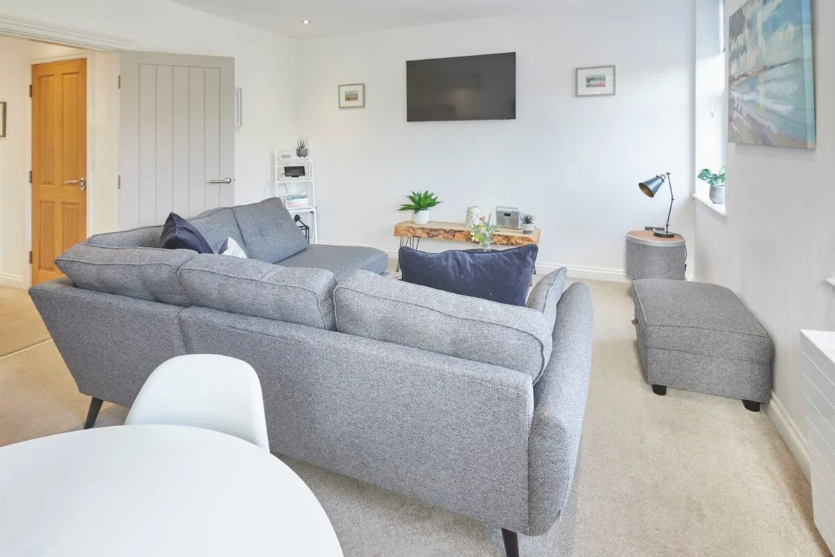 A bright living room with gray seating facing a wall-mounted television.