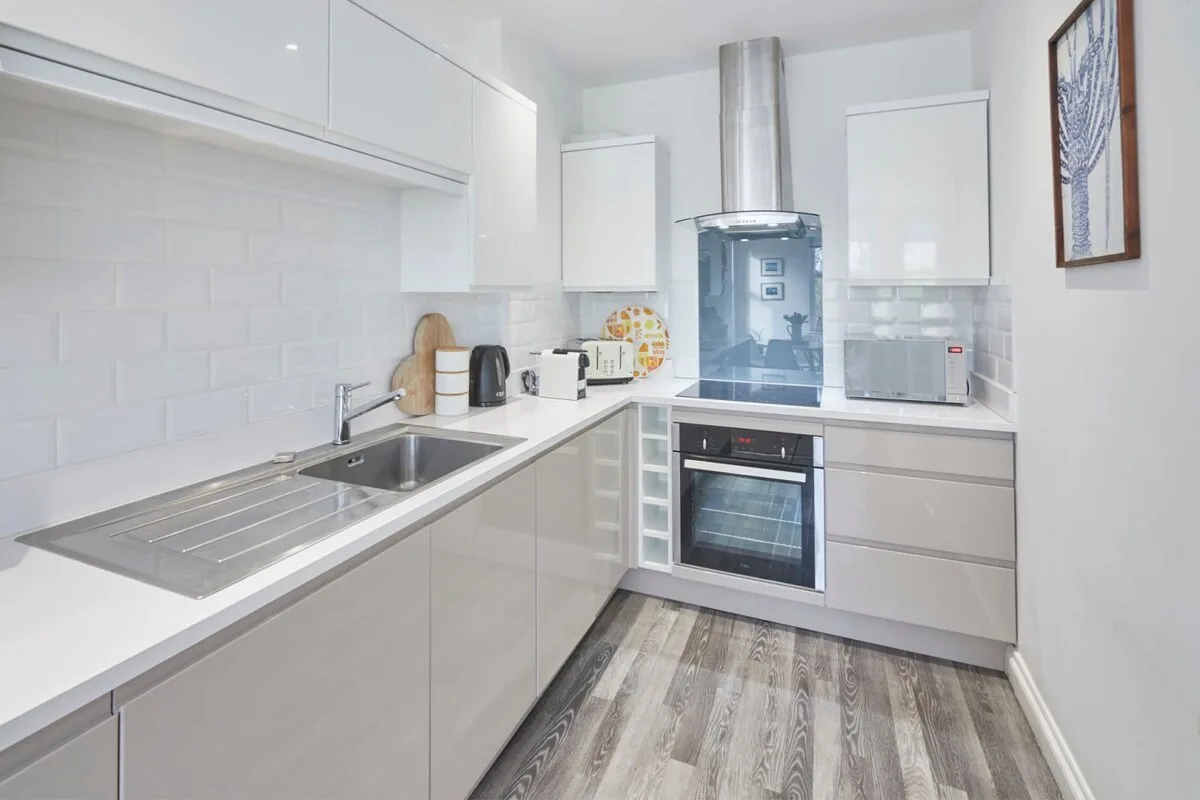 A bright modern kitchen with white cabinetry and built-in appliances.