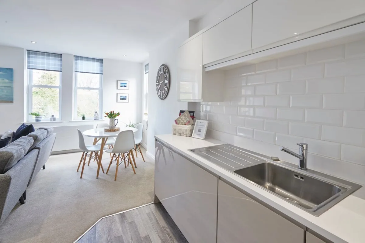 A bright open-plan kitchen and dining area with a sink and table.