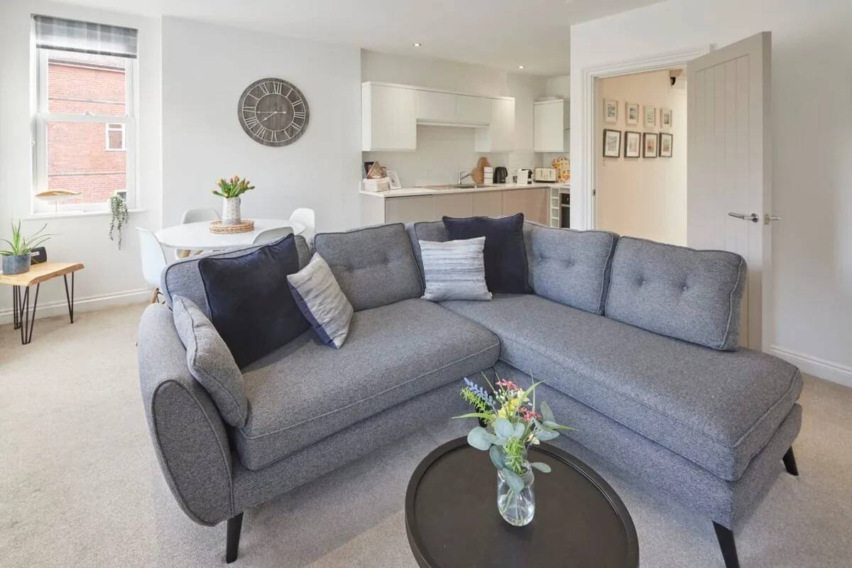 A bright living room with gray seating and a dining area by the window.
