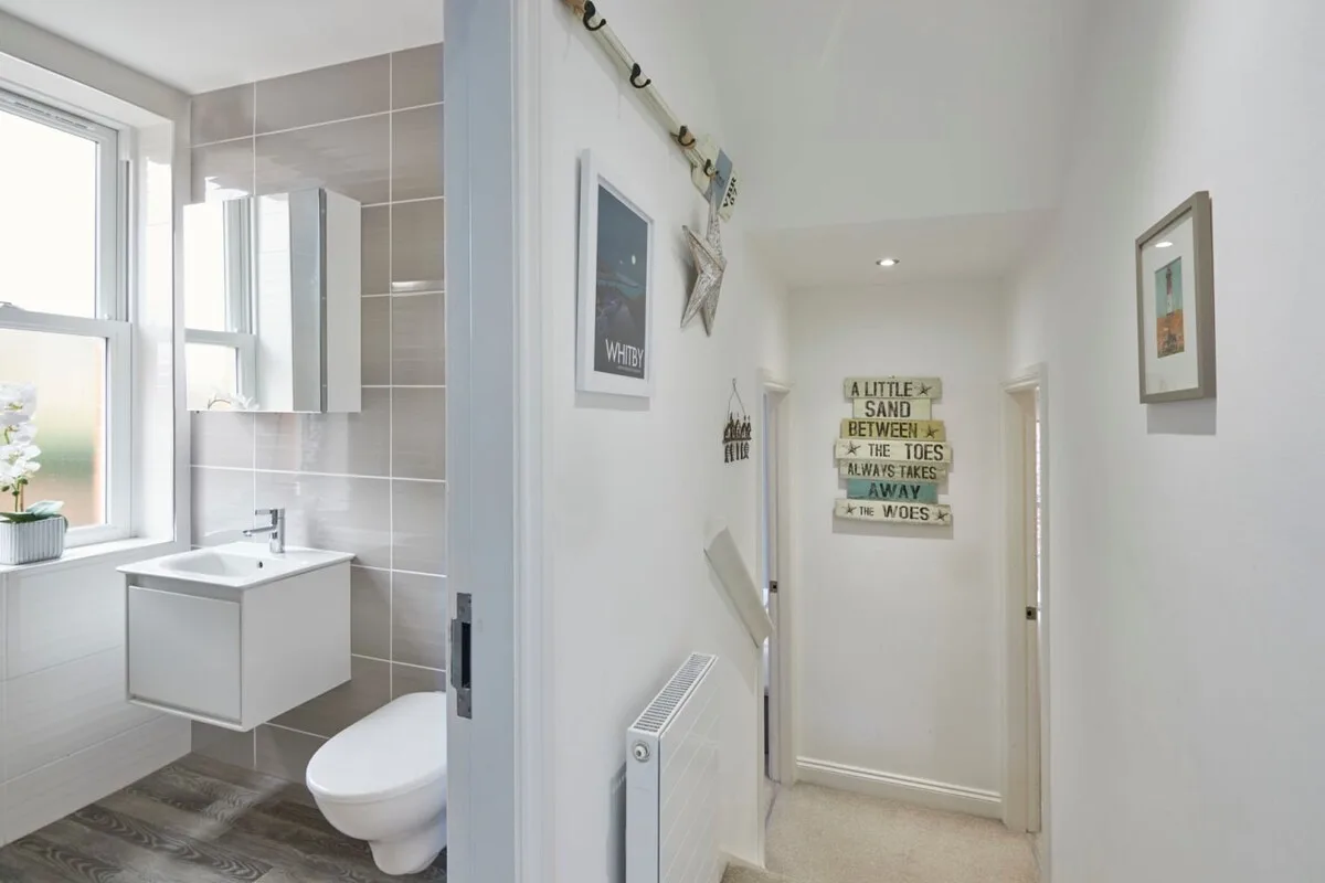 A bathroom with a sink and toilet opens onto a hallway.