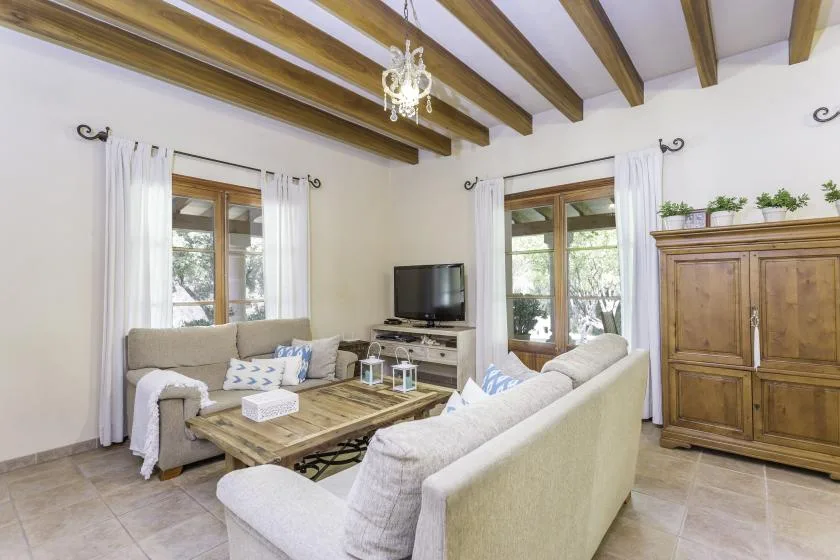 A living room with light-colored seating, a wooden coffee table, and a television.
