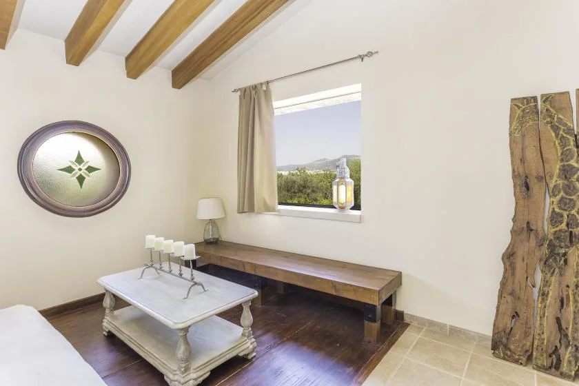 A bright living area with exposed ceiling beams and a window overlooking greenery.