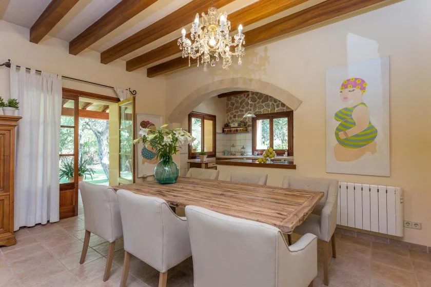 A dining area with a wooden table, upholstered seating, and a chandelier.