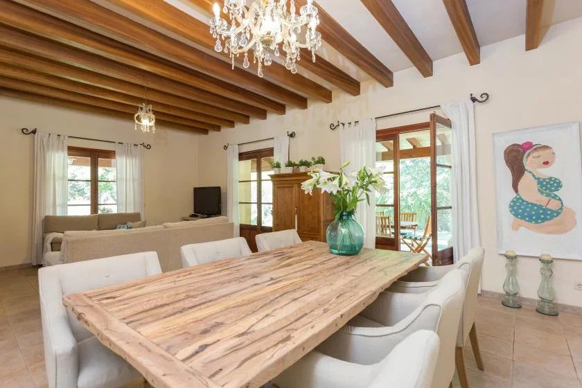 A dining room with a long wooden table and white upholstered seating.