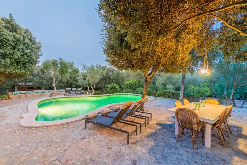 A garden patio with a swimming pool, lounge seating, and an outdoor dining table.