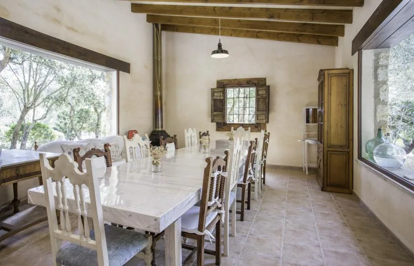 A long dining table and chairs fill a bright room with large windows.