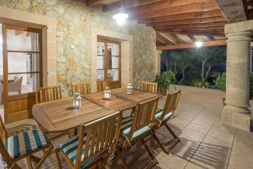A covered patio dining area with a long wooden table and chairs.