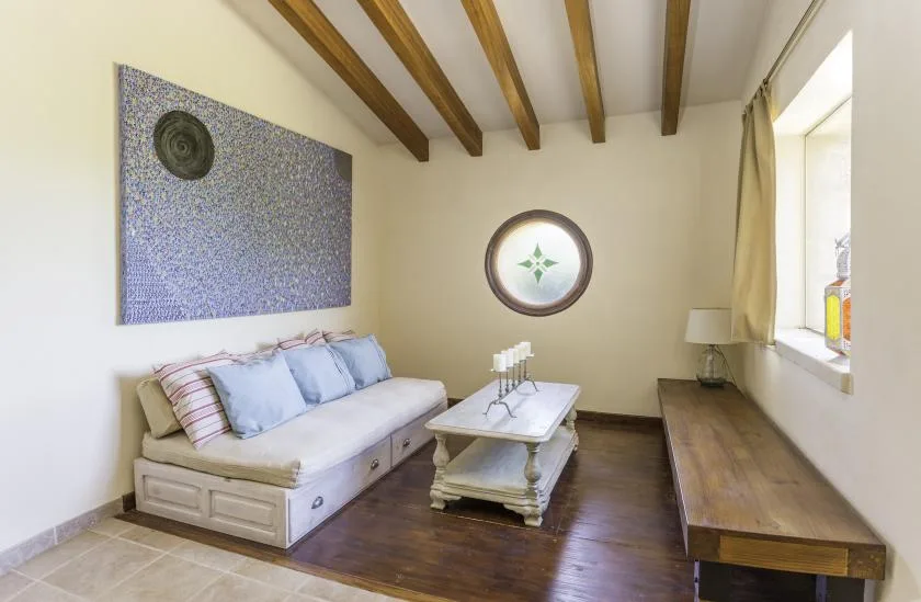 A sitting room with cushioned seating, a coffee table, and exposed ceiling beams.
