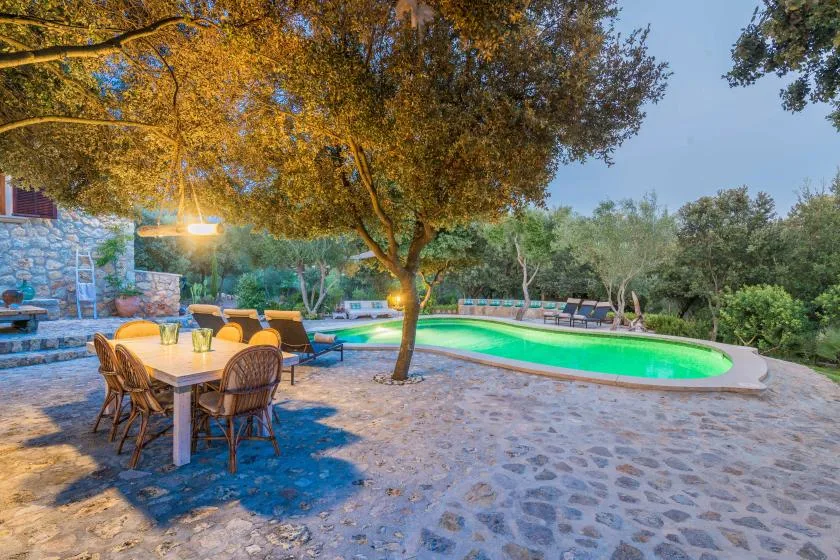 An outdoor pool beside a stone patio with a dining table and seating.