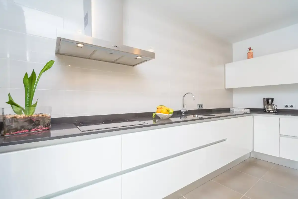 Una cocina moderna y luminosa con armarios blancos y una encimera.