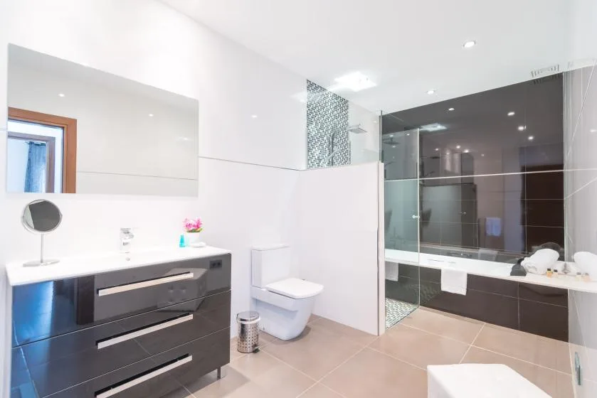 Un baño luminoso con lavabo, inodoro y ducha de vidrio.
