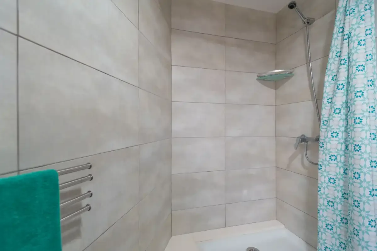 Un baño alicatado con ducha, cortina estampada y toallero.