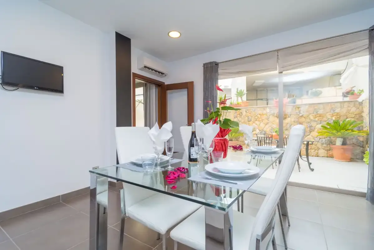 Un comedor luminoso con una mesa de cristal junto a puertas correderas que dan a un patio.