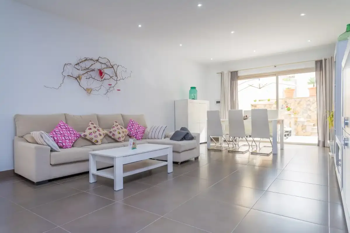 Un salón luminoso con asientos y una mesa de comedor junto a grandes ventanales.
