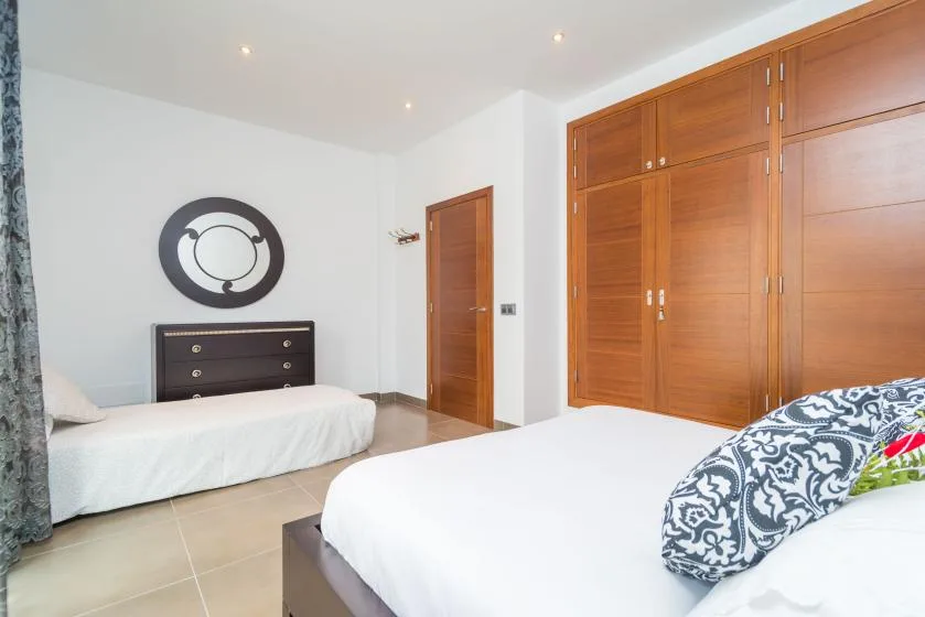 Un dormitorio luminoso con dos camas y armarios de madera.